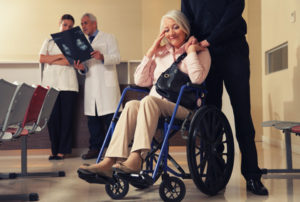 Senior woman on wheelchair with her husband and doctors analyzin